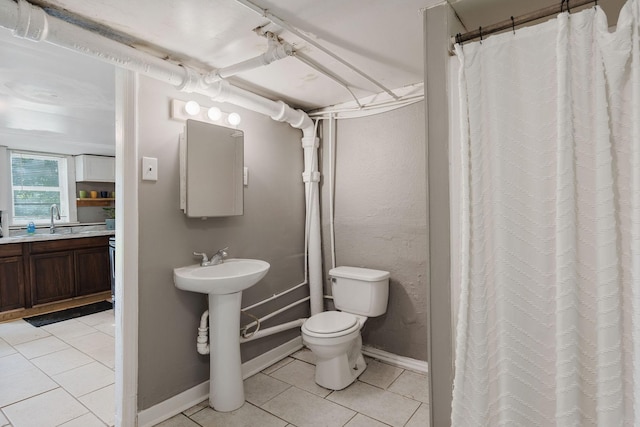 full bathroom featuring curtained shower, toilet, a sink, tile patterned flooring, and baseboards