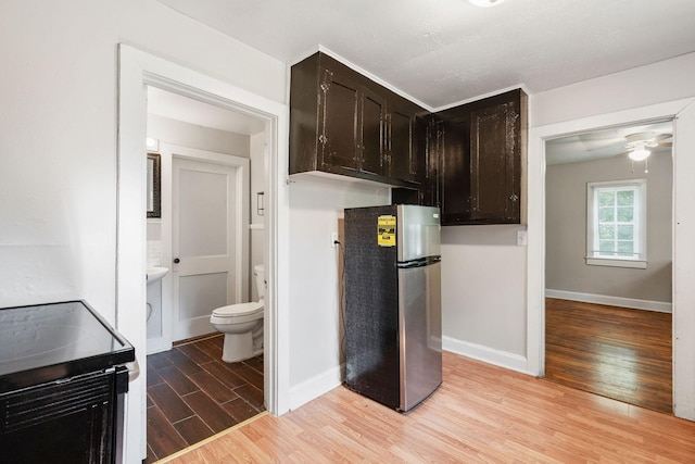 kitchen with light wood finished floors, freestanding refrigerator, dark brown cabinetry, range with electric cooktop, and baseboards