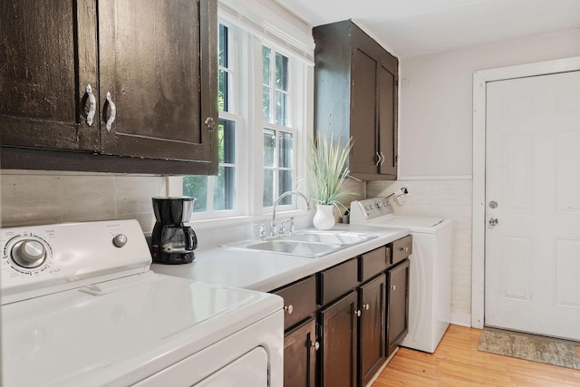 washroom featuring light wood-style floors, washing machine and dryer, cabinet space, and a sink