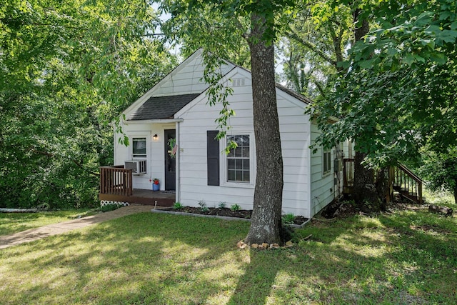 bungalow with a front lawn, roof with shingles, and cooling unit