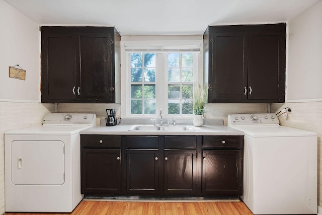 laundry area featuring cabinet space, light wood-style flooring, a sink, and independent washer and dryer