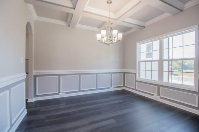 spare room with coffered ceiling, dark wood-type flooring, crown molding, a chandelier, and beam ceiling