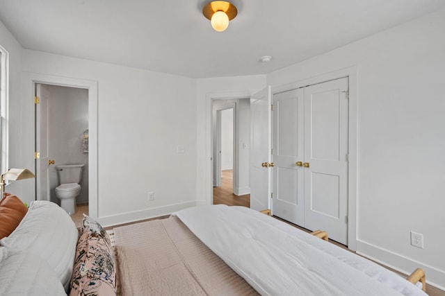 bedroom featuring ensuite bath, baseboards, and a closet