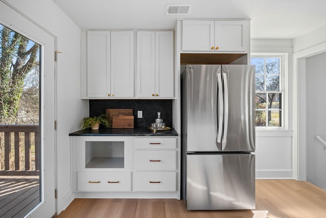 kitchen featuring visible vents, decorative backsplash, freestanding refrigerator, white cabinetry, and light wood-type flooring