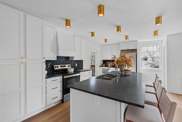 kitchen with premium range hood, a breakfast bar, a sink, appliances with stainless steel finishes, and dark countertops