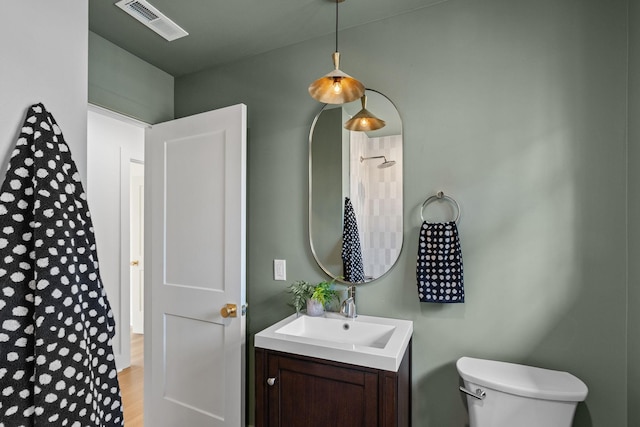 bathroom featuring toilet, visible vents, wood finished floors, and vanity