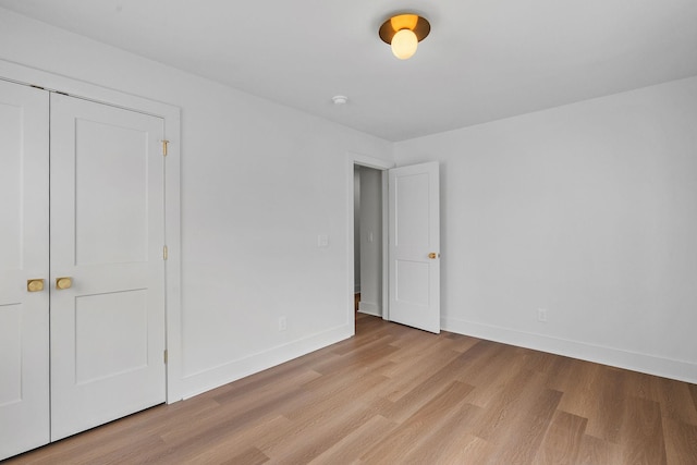 unfurnished bedroom with light wood-type flooring, baseboards, and a closet