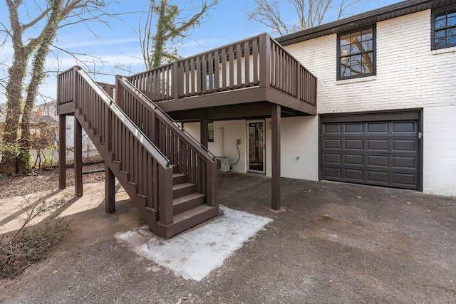 view of front facade with a garage, stairway, a deck, and brick siding