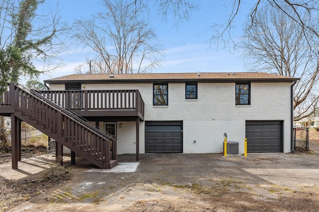 exterior space with an attached garage, stairs, central AC unit, and brick siding