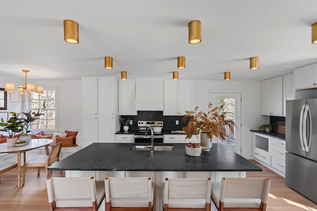 kitchen featuring stainless steel appliances, a sink, white cabinetry, light wood finished floors, and breakfast area