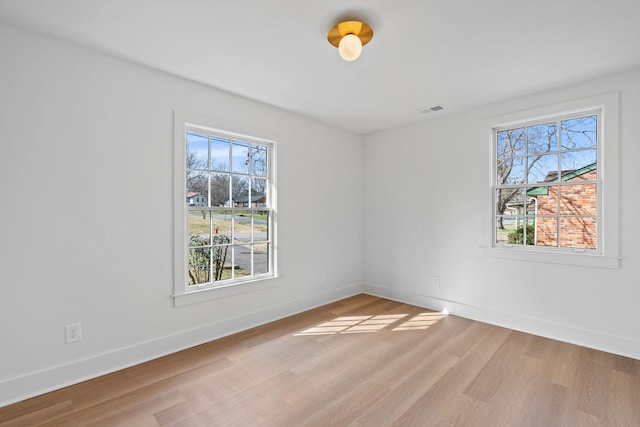 empty room featuring baseboards, visible vents, and light wood finished floors