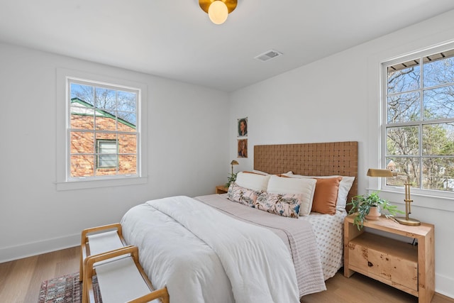 bedroom with baseboards, visible vents, and wood finished floors