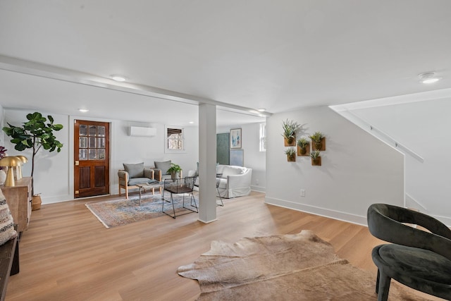 living room featuring a wall unit AC, light wood-style flooring, and baseboards