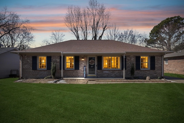 single story home featuring a front lawn, roof with shingles, and brick siding