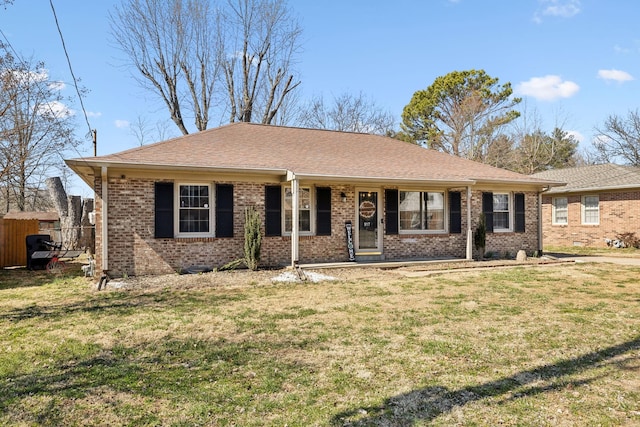 ranch-style home featuring brick siding, fence, a front lawn, and roof with shingles