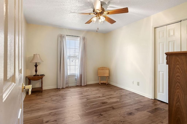 interior space with a textured ceiling, wood finished floors, and baseboards