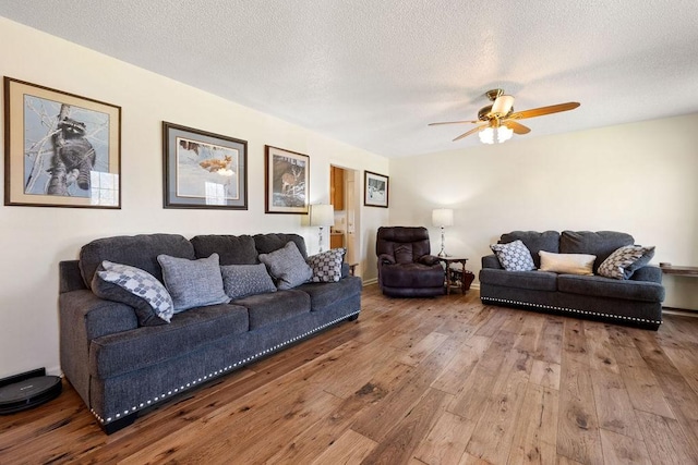 living area featuring a textured ceiling, hardwood / wood-style flooring, and a ceiling fan