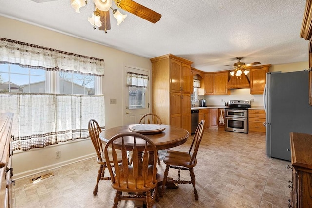 dining space with visible vents, ceiling fan, a textured ceiling, and baseboards