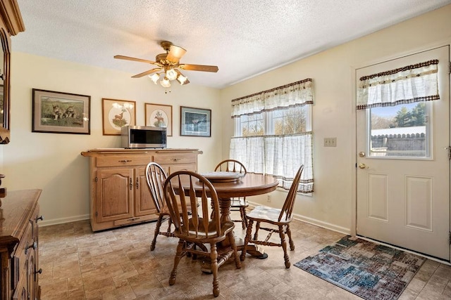 dining room featuring a textured ceiling, a ceiling fan, and baseboards