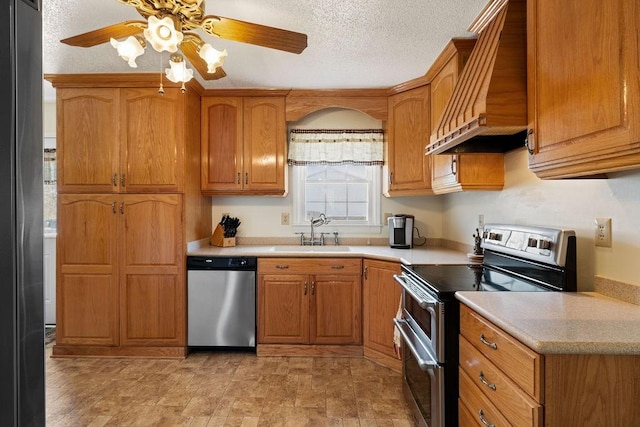 kitchen featuring a sink, light countertops, appliances with stainless steel finishes, custom exhaust hood, and brown cabinets