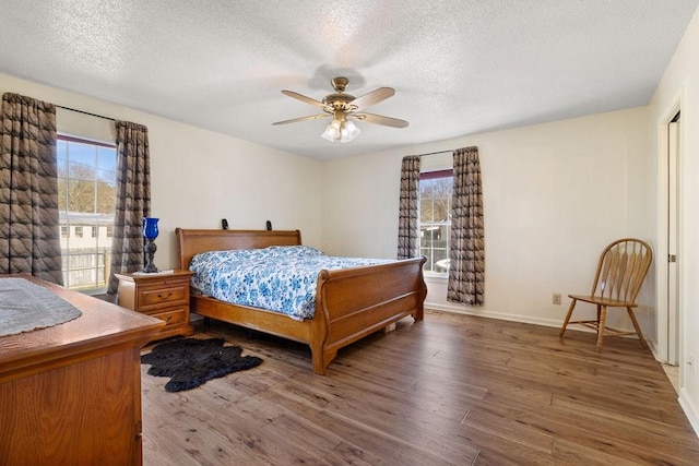 bedroom with a textured ceiling, multiple windows, and wood finished floors