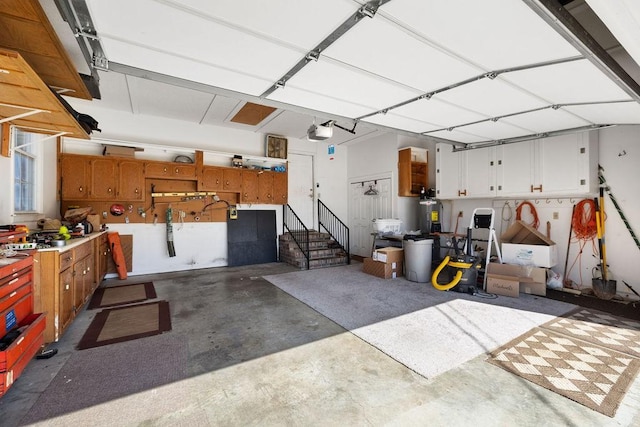 garage with electric water heater, a workshop area, and a garage door opener