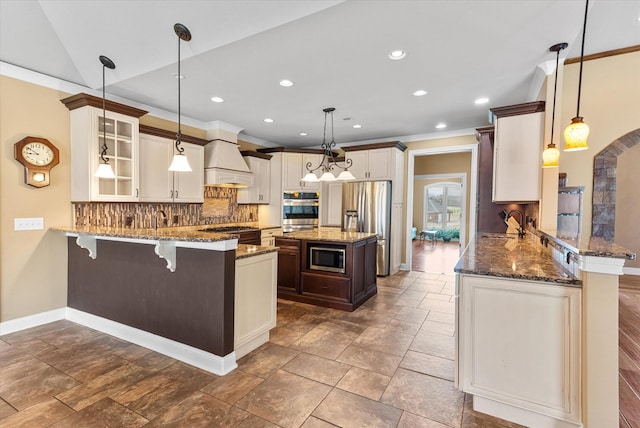 kitchen with a peninsula, appliances with stainless steel finishes, and dark stone countertops