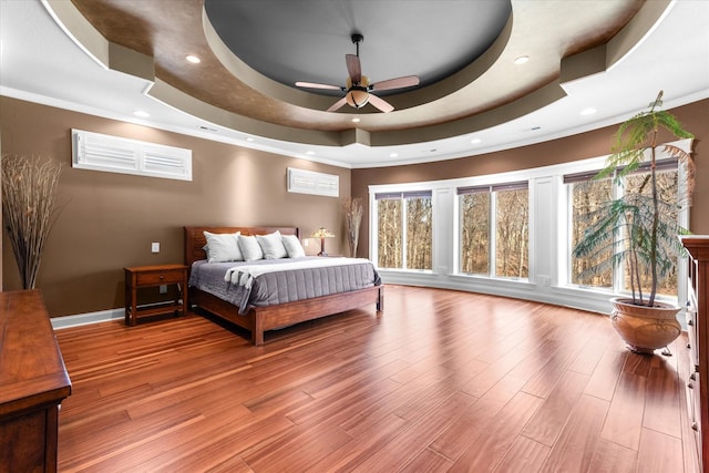 bedroom with baseboards, a tray ceiling, wood finished floors, and recessed lighting