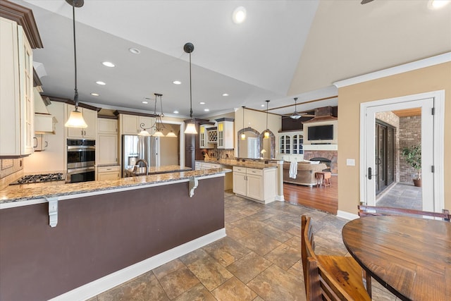 kitchen featuring light stone counters, a peninsula, stainless steel appliances, a ceiling fan, and a kitchen bar