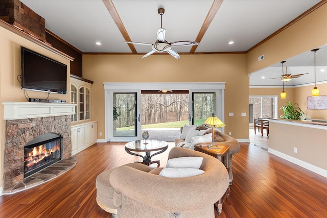 living area featuring a fireplace, a ceiling fan, baseboards, ornamental molding, and hardwood / wood-style floors