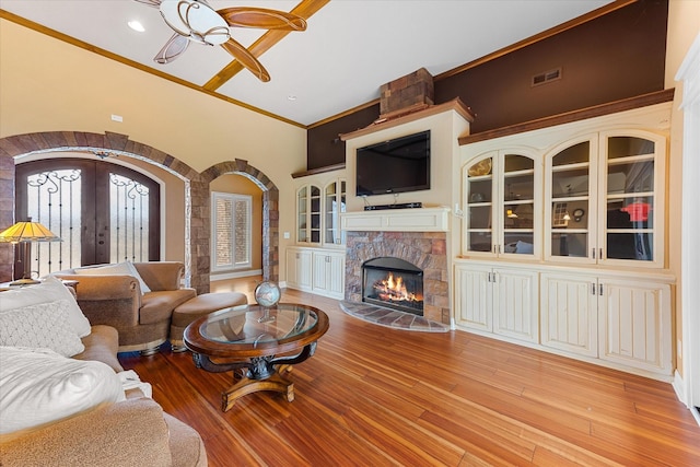 living room featuring visible vents, arched walkways, crown molding, french doors, and light wood-type flooring