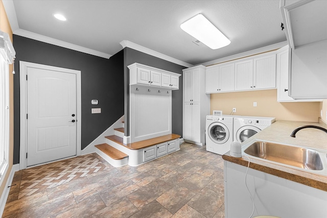 laundry area with crown molding, cabinet space, a sink, separate washer and dryer, and baseboards