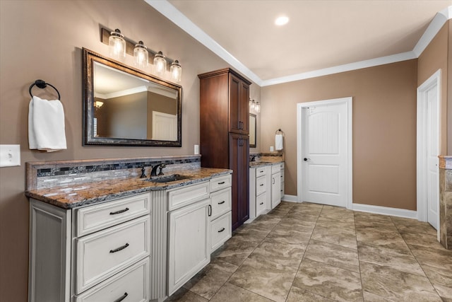 full bathroom with crown molding, two vanities, a sink, and baseboards