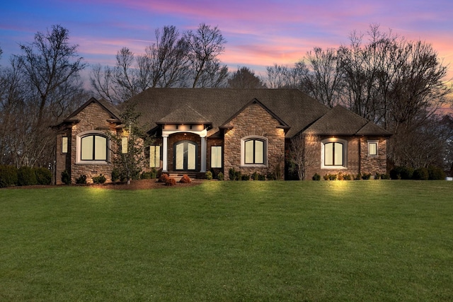 french provincial home with roof with shingles and a yard