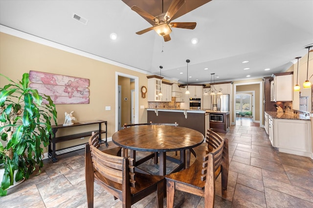 dining room featuring visible vents, a ceiling fan, ornamental molding, vaulted ceiling, and stone tile flooring