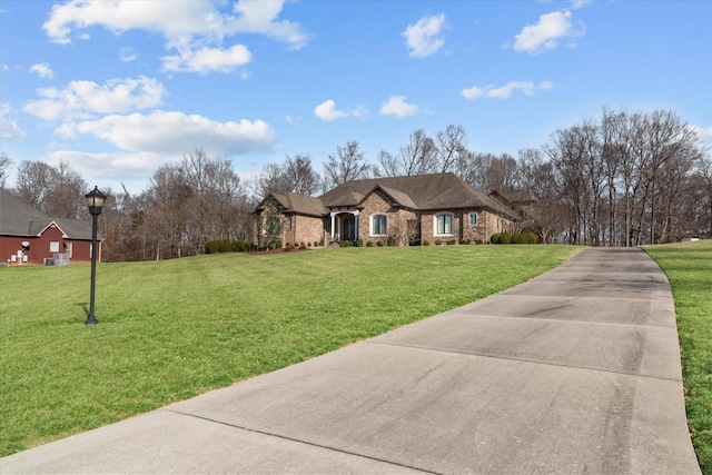 french country style house featuring concrete driveway, brick siding, and a front lawn