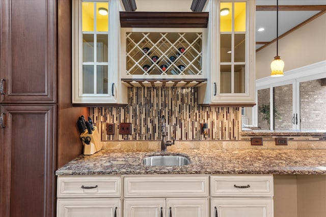 bar with hanging light fixtures, tasteful backsplash, wet bar, and a sink