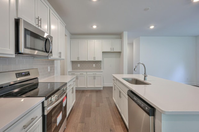 kitchen with a sink, white cabinetry, light countertops, appliances with stainless steel finishes, and light wood-type flooring