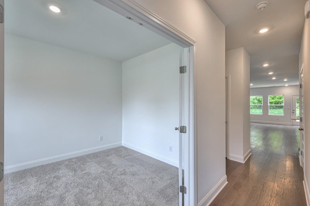 hall with dark wood-type flooring, recessed lighting, and baseboards