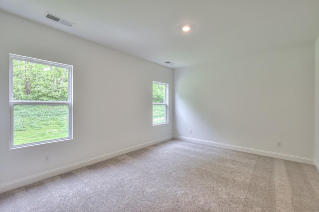 spare room featuring visible vents, light carpet, and baseboards