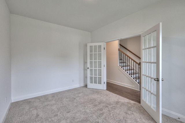 carpeted empty room with french doors, stairway, and baseboards