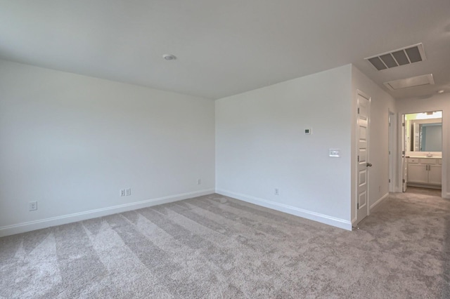 empty room with baseboards, light colored carpet, visible vents, and attic access