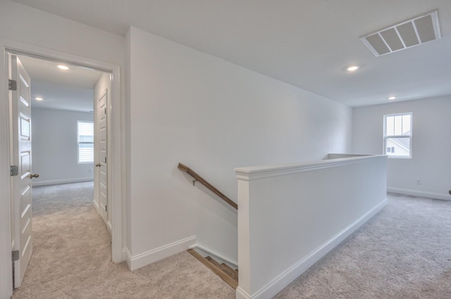 corridor with visible vents, light carpet, and an upstairs landing