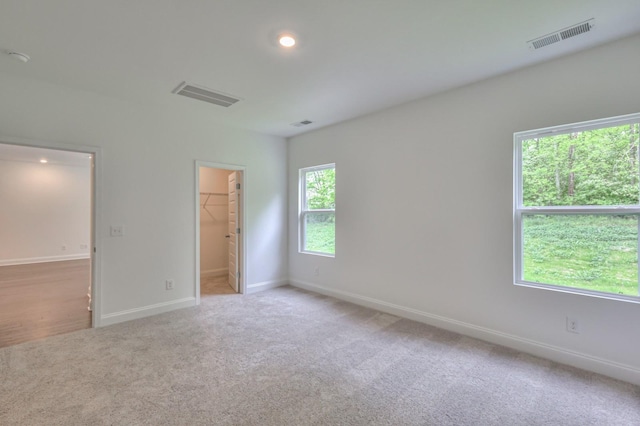 unfurnished bedroom with baseboards, a spacious closet, visible vents, and carpet flooring