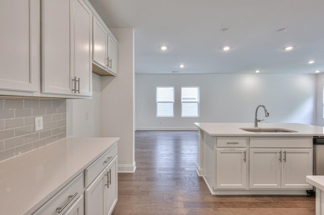 kitchen with wood finished floors, a sink, white cabinetry, light countertops, and tasteful backsplash