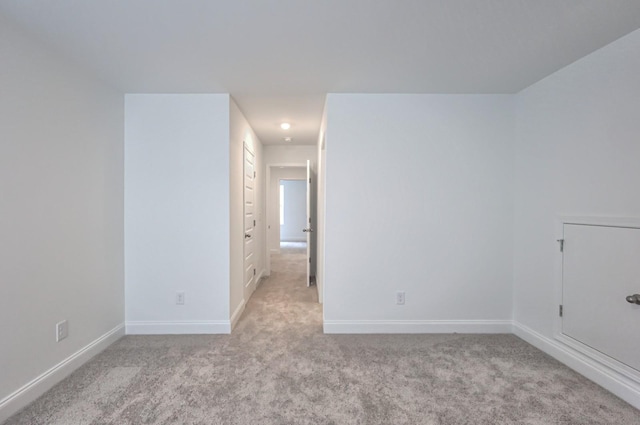 unfurnished room featuring baseboards and light colored carpet