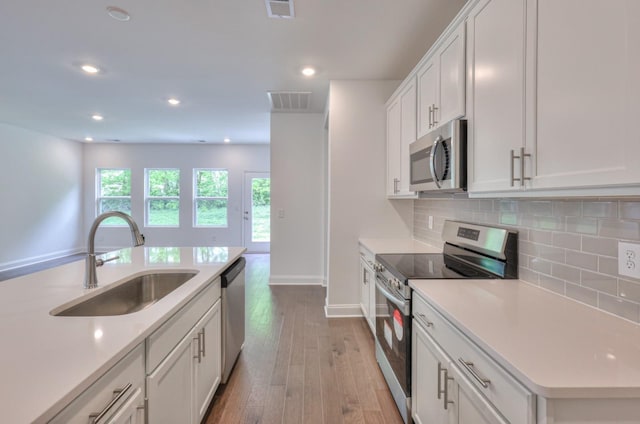 kitchen featuring stainless steel appliances, tasteful backsplash, light countertops, visible vents, and a sink