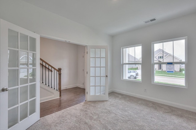 unfurnished room with carpet floors, french doors, baseboards, and stairs