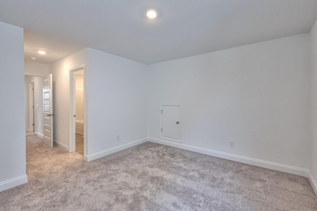 spare room featuring light carpet and baseboards