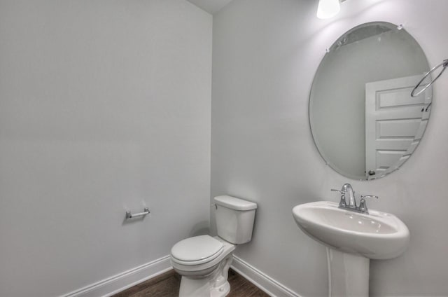 half bath featuring toilet, baseboards, and wood finished floors